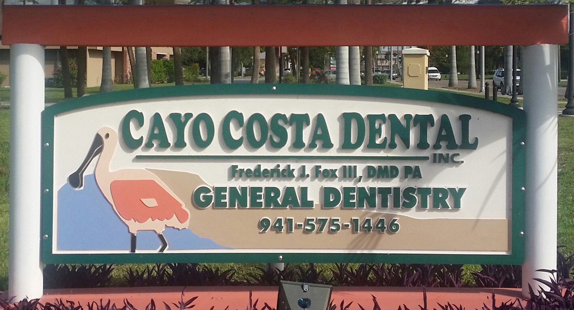 The image is a photograph of a sign for Cayo Costa Dental, which includes the names of two individuals and their professional titles.