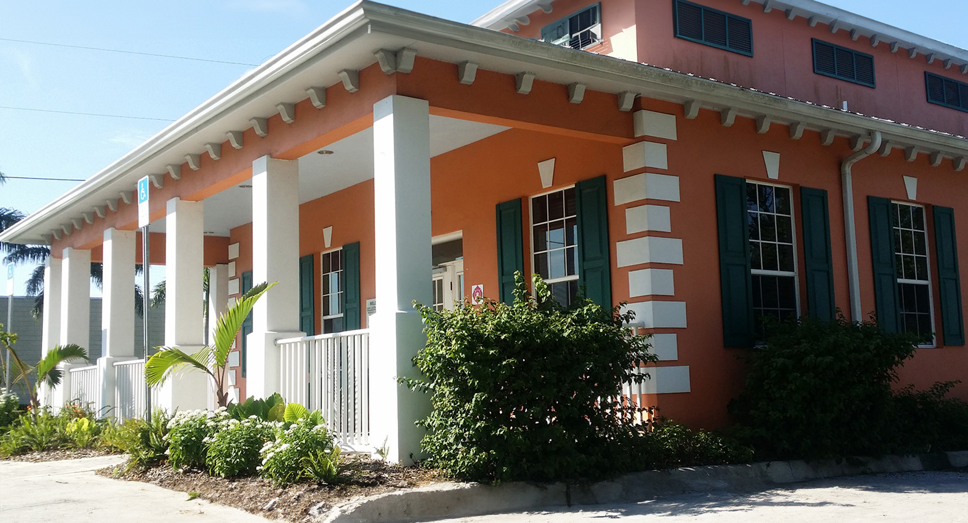 The image depicts a building with an orange exterior and white trim, featuring a covered porch area.