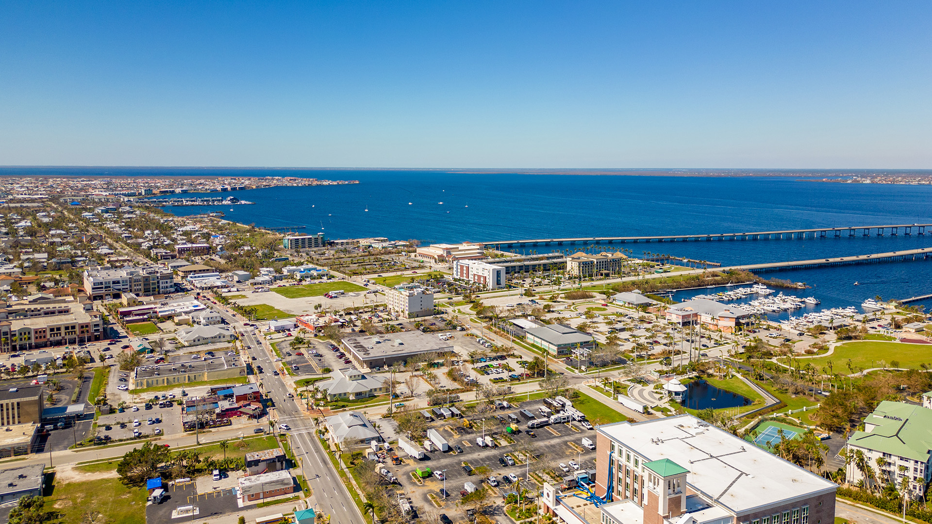 Aerial view of a coastal cityscape with a bridge, buildings, and waterways.
