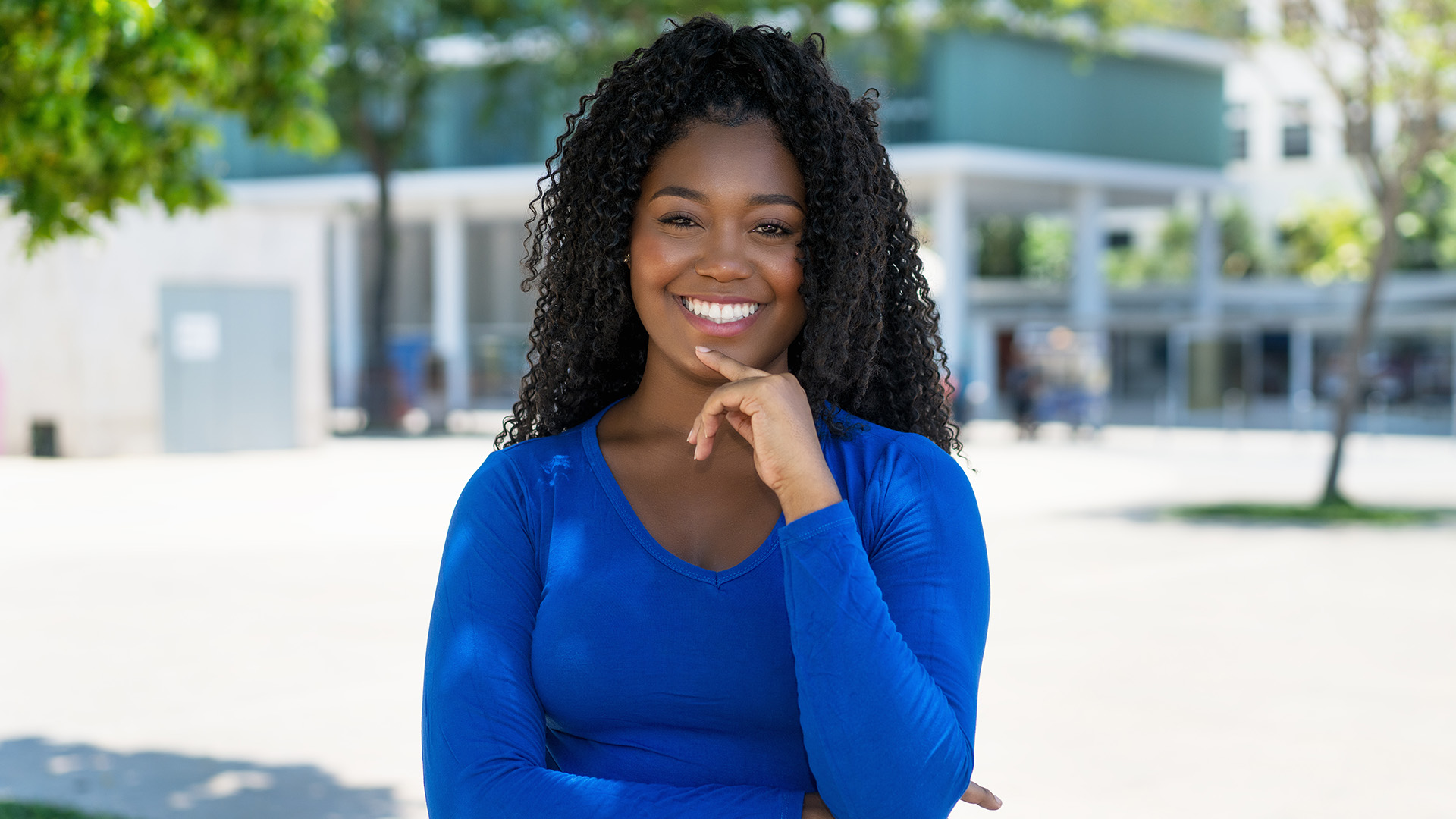 A woman with a broad smile is standing outdoors, posing for the camera.