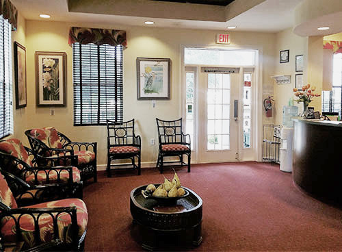 The image shows an interior view of a cozy waiting area with seating, a coffee table, and decorative elements.
