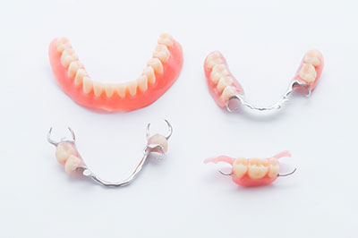 Three sets of dentures displayed on a white background, each with a full set of upper and lower teeth.