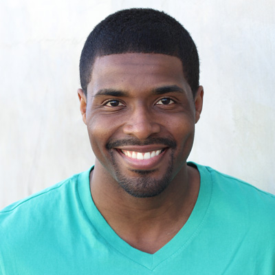An elderly couple smiling at the camera, with the man on the left and the woman on the right.