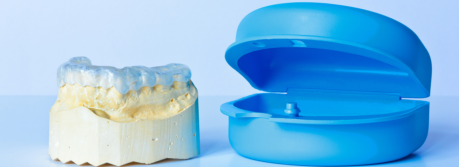 The image displays a pair of blue, plastic teeth models alongside a yellow dental impression material.