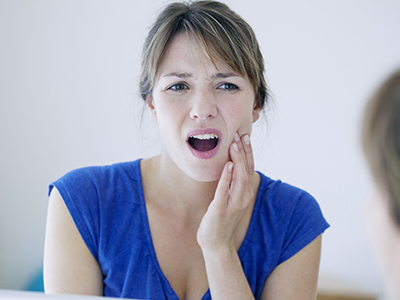 The image shows a woman with her mouth open, expressing surprise or shock, as she looks in the mirror.