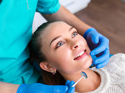 A dental hygienist performing a teeth cleaning procedure on a patient in a clinical setting.