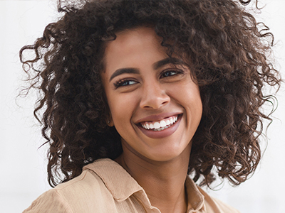 The image features a woman with curly hair and a smiling expression, looking directly at the camera.